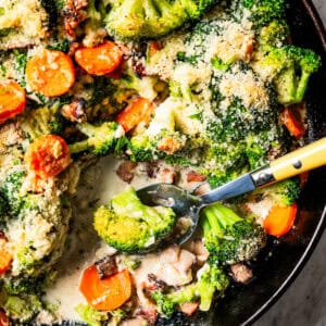 Broccoli and cheese in a skillet with a spoon for serving.