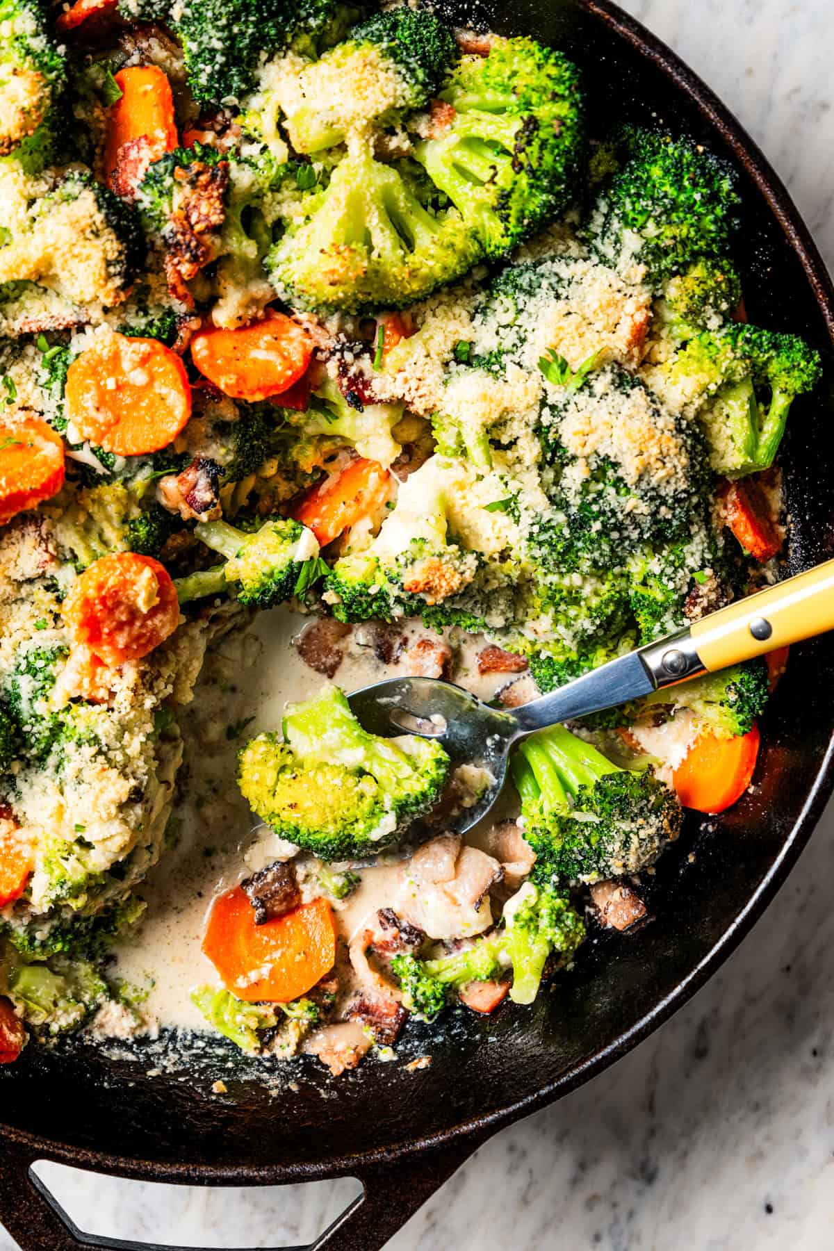 Broccoli and cheese in a skillet with a spoon for serving.