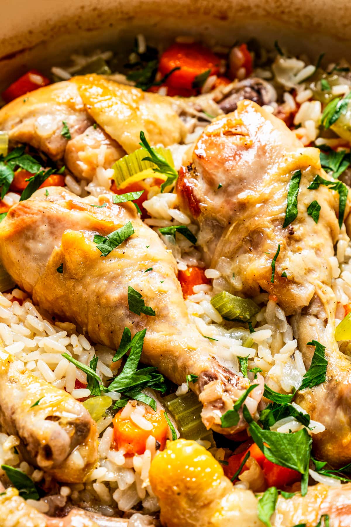 Close-up of chicken drumsticks set over cooked rice and vegetables.