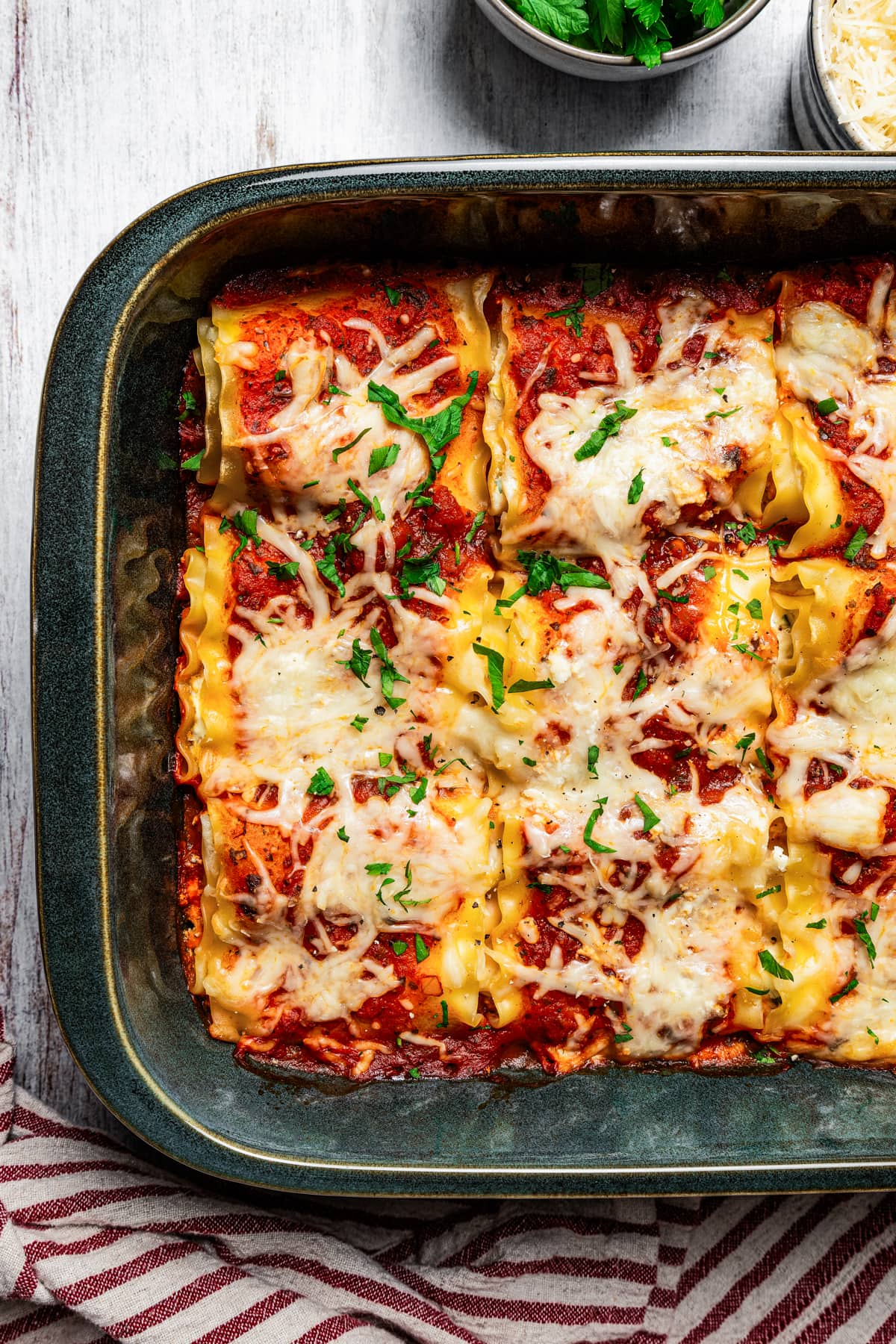 Overhead view of baked lasagna roll ups in a baking pan.