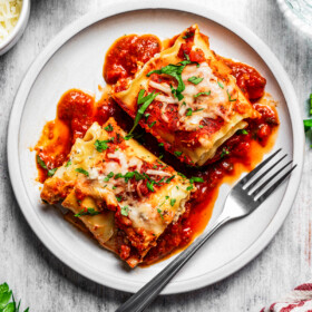 Overhead image of two lasagna roll-ups served on a white dinner plate.