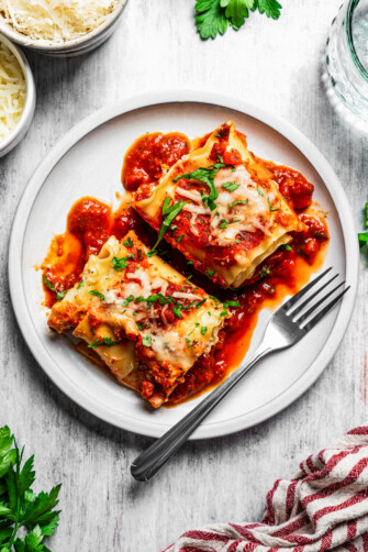 Overhead image of two lasagna roll-ups served on a white dinner plate.