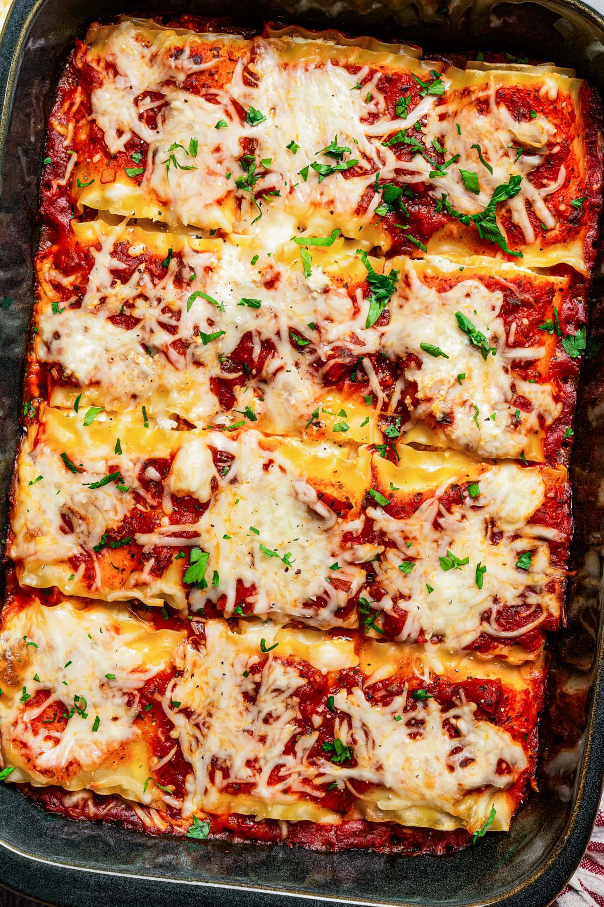 Baked lasagna roll ups in a baking dish.