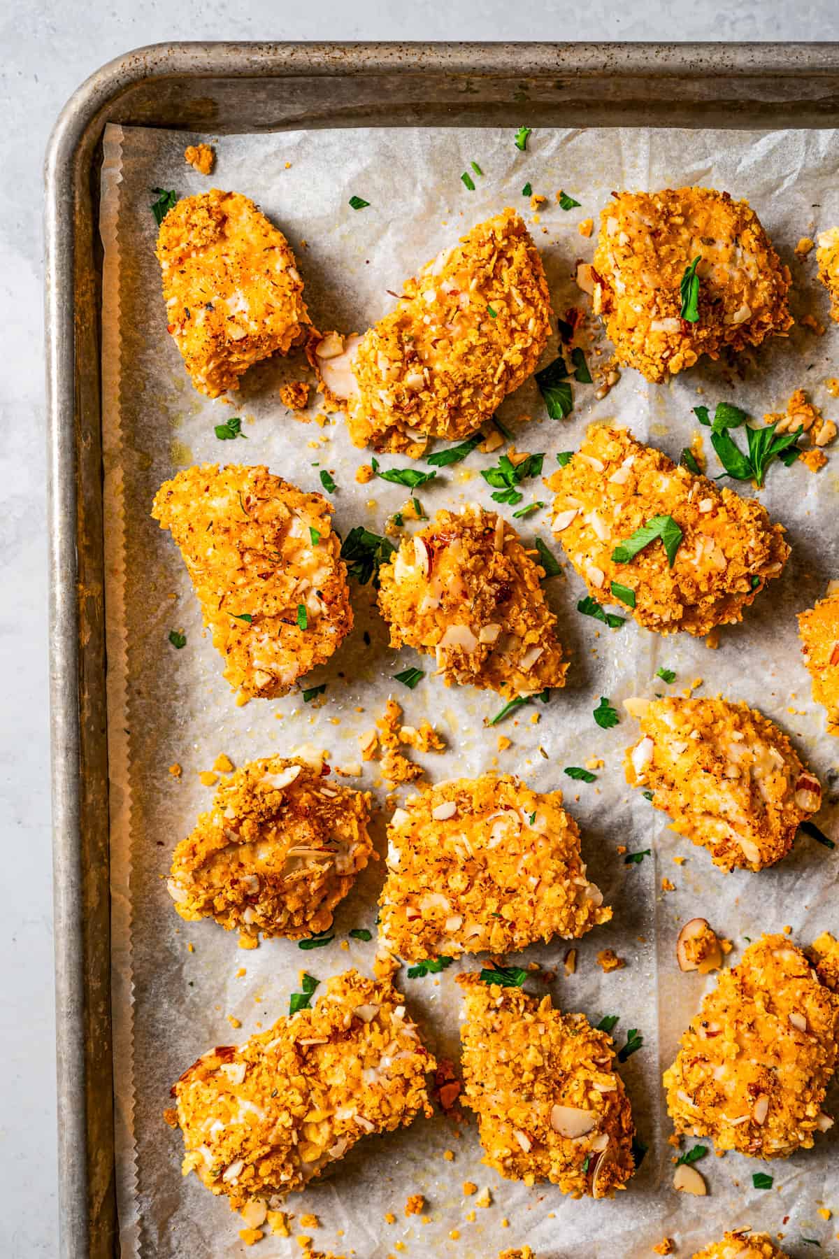 Pecan crusted chicken on a parchment-lined baking sheet.