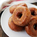 A stack of pumpkin donuts glazed with salted caramel sauce on a white plate.