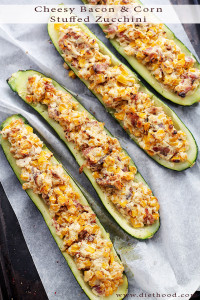 Overhead image of four zucchini boats stuffed with cheese, corn, and bacon.