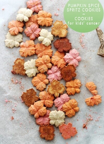 A bunch of different colored, pumpkin flavored spritz cookies on parchment paper