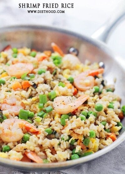 Shrimp fried rice in a pan with carrots and peas.