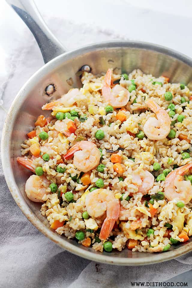 a stainless steel skillet with shrimp, rice, and vegetables.