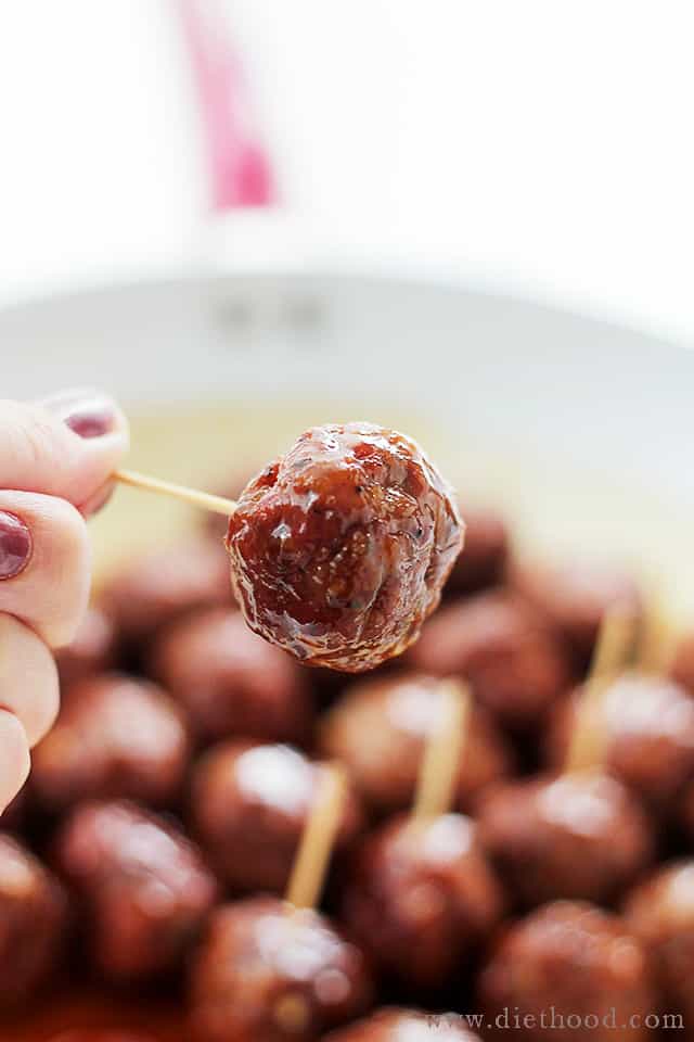 A Brown Sugar-Glazed Meatball being held on a toothpick