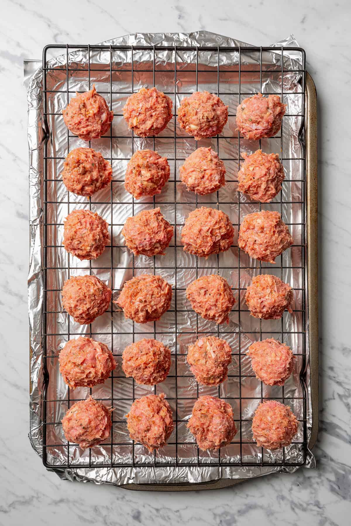 Uncooked turkey meatballs on a wire rack set over a baking pan.
