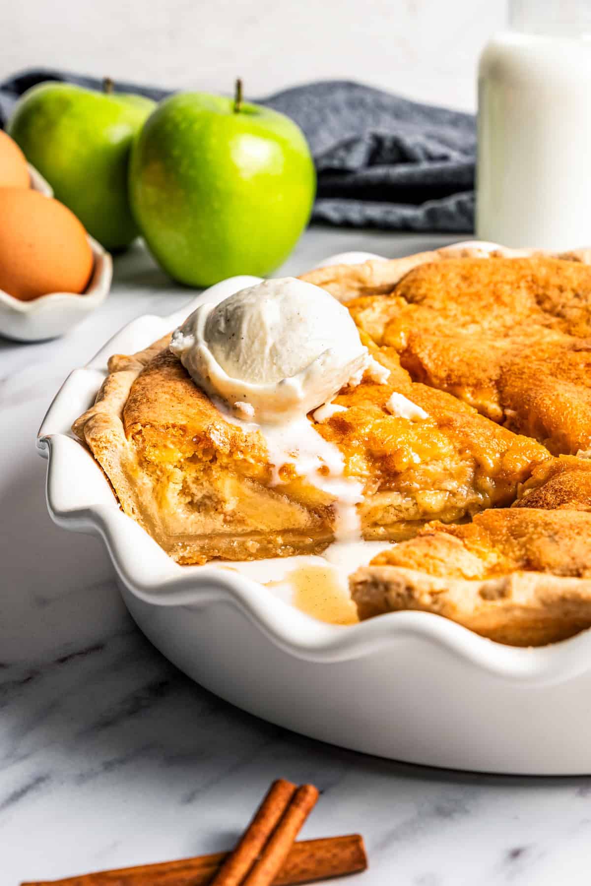This apple pie cake has juicy caramel apples layered into a buttery crust, baked beneath a soft, sweet cake layer. It's easier than pie! Apple pie cake in a deep dish pie plate.