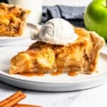 A slice of apple pie cake topped with a scoop of vanilla ice cream on a plate.