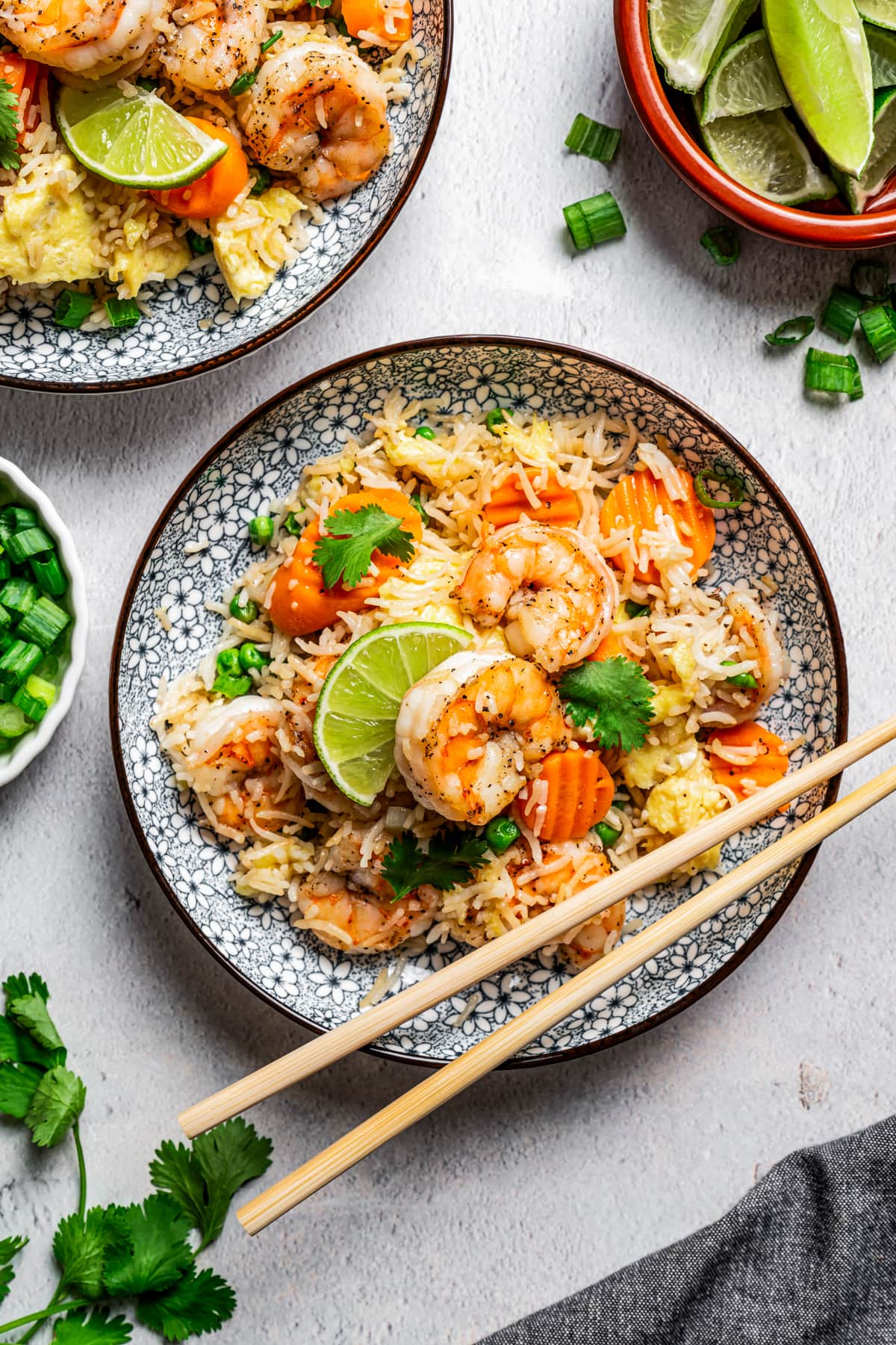 Shrimp fried rice served on dinner plates garnished with lime wedges, and a pair of chopsticks placed on the side of the plate.