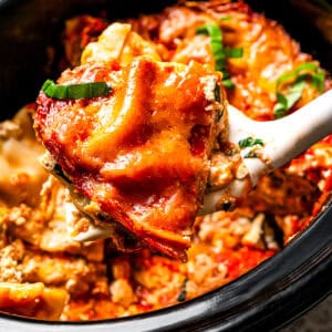 A scoop of crock pot lasagna being served from the crock pot.