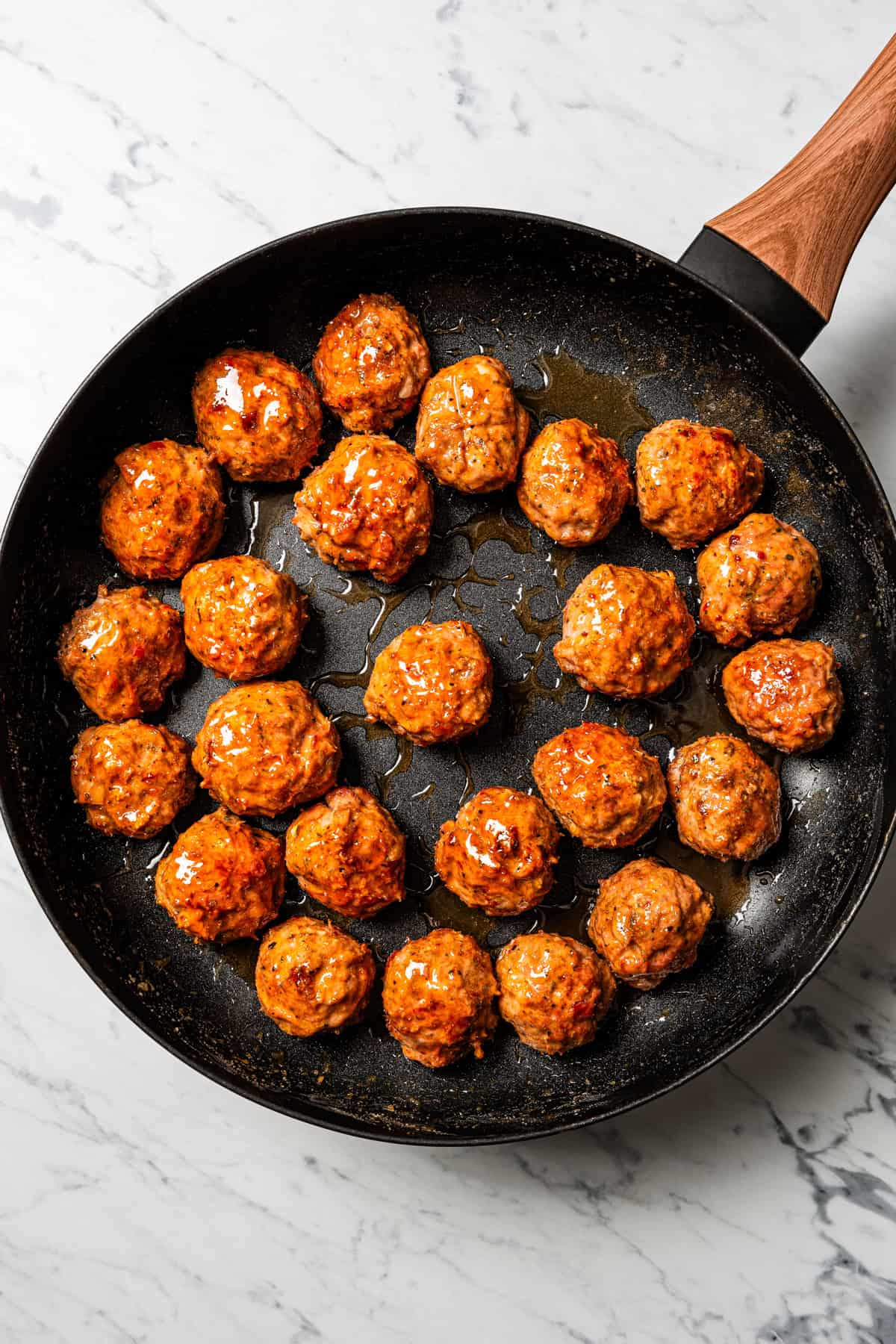 Overhead view of glazed meatballs in a skillet.