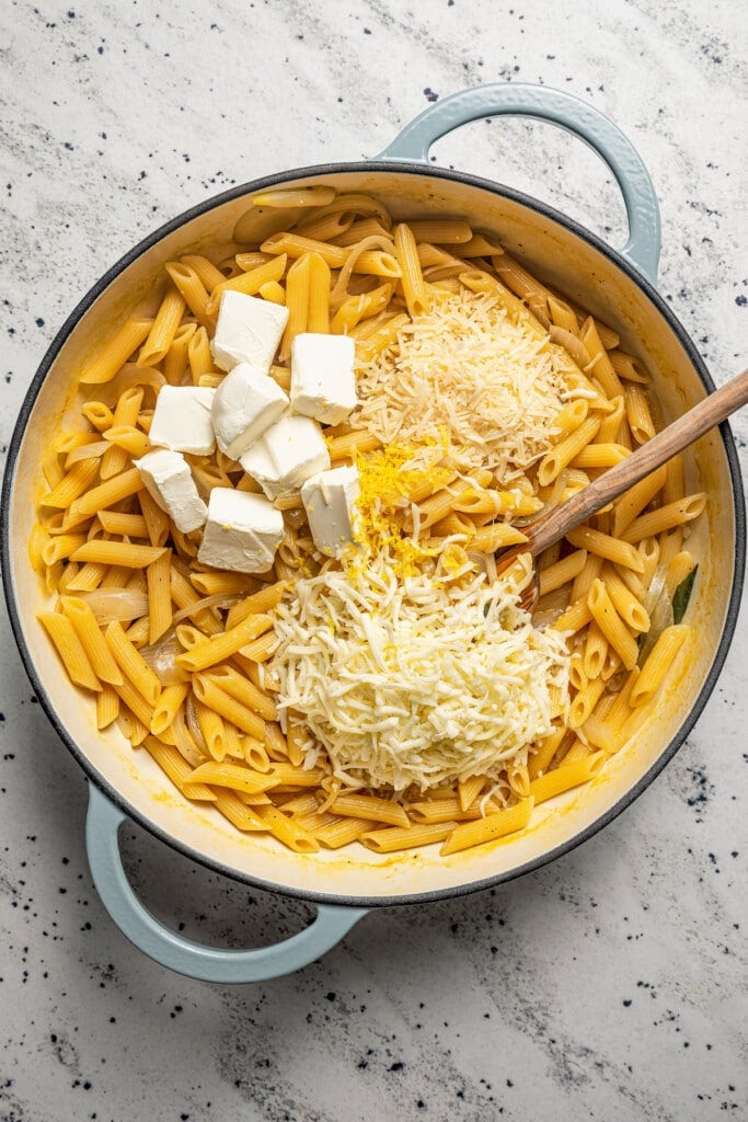 Adding the different kinds of cheese into the pasta to make the sauce. 