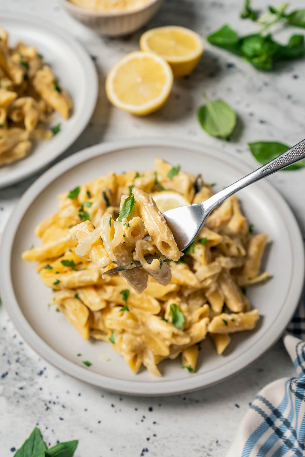 This 20-minute lemon pasta recipe with tangy cream cheese is a garlicky one-pot dinner full of zesty goodness. Grabbing creamy lemon pasta with a fork.