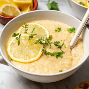 A bowl of lemon rice soup garnished with lemon slices and thyme sprigs.