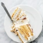 A slice of pumpkin icebox cake served on a dessert plate with a fork cutting into the cake.