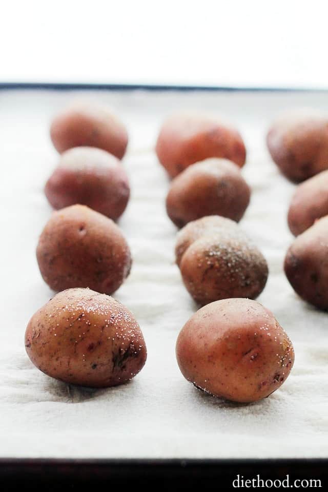 Boiled potatoes in rows on a lined baking sheet.