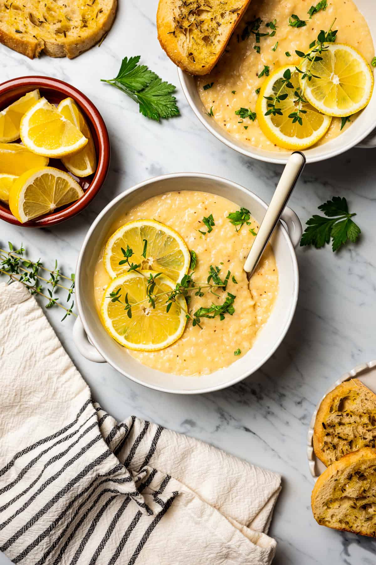 Weekly Menu Plan A bowl of lemon rice soup garnished with lemon slices and thyme sprigs is next to a small dish filled with lemon wedges and a second bowl of soup.