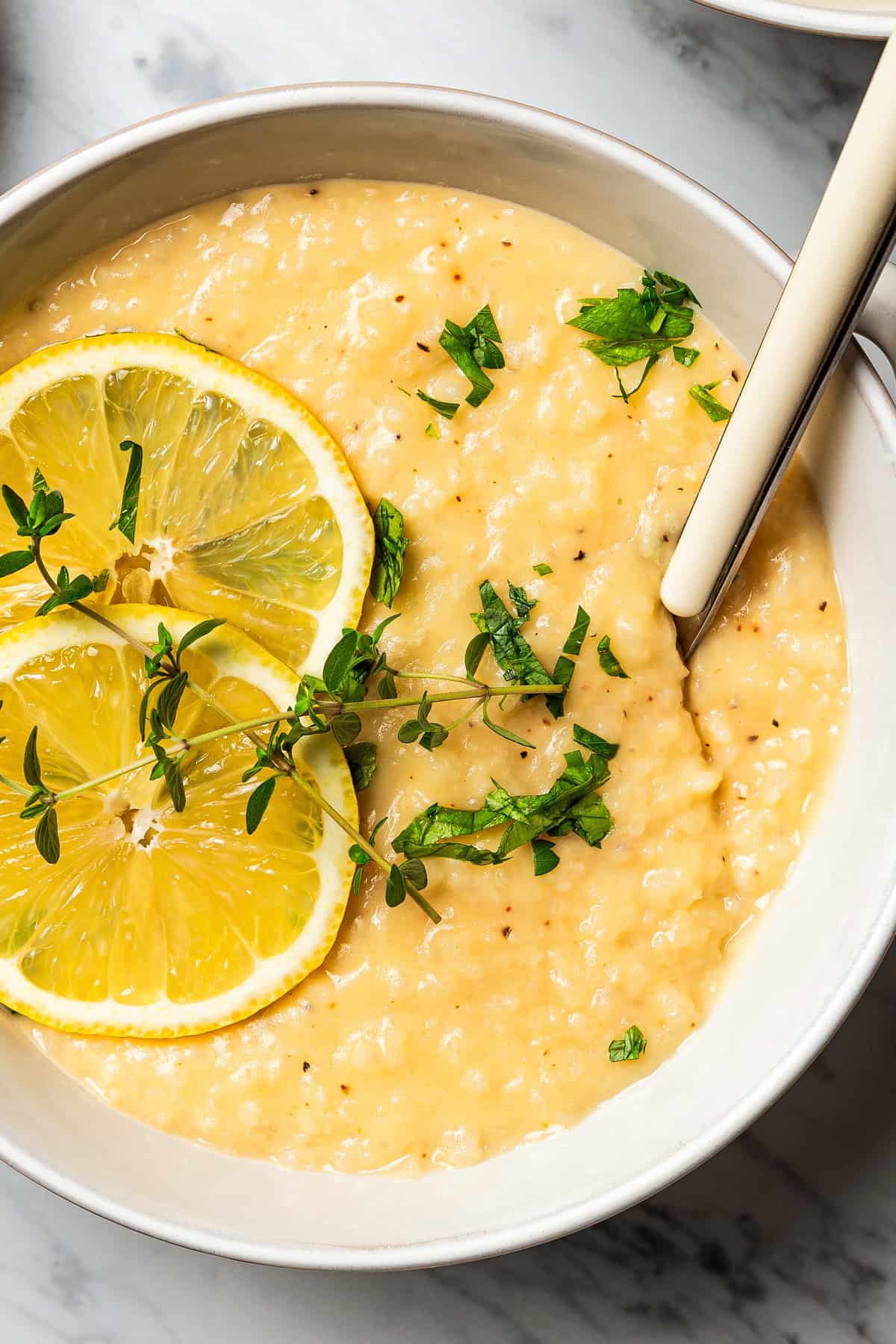 Close-up photo of lemon rice soup served in a bowl and garnished with lemon slices.