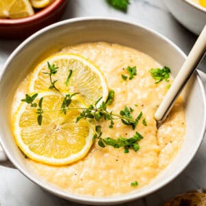 Lemon Rice Soup in a bowl with a garnish of lemon slices and green herbs.