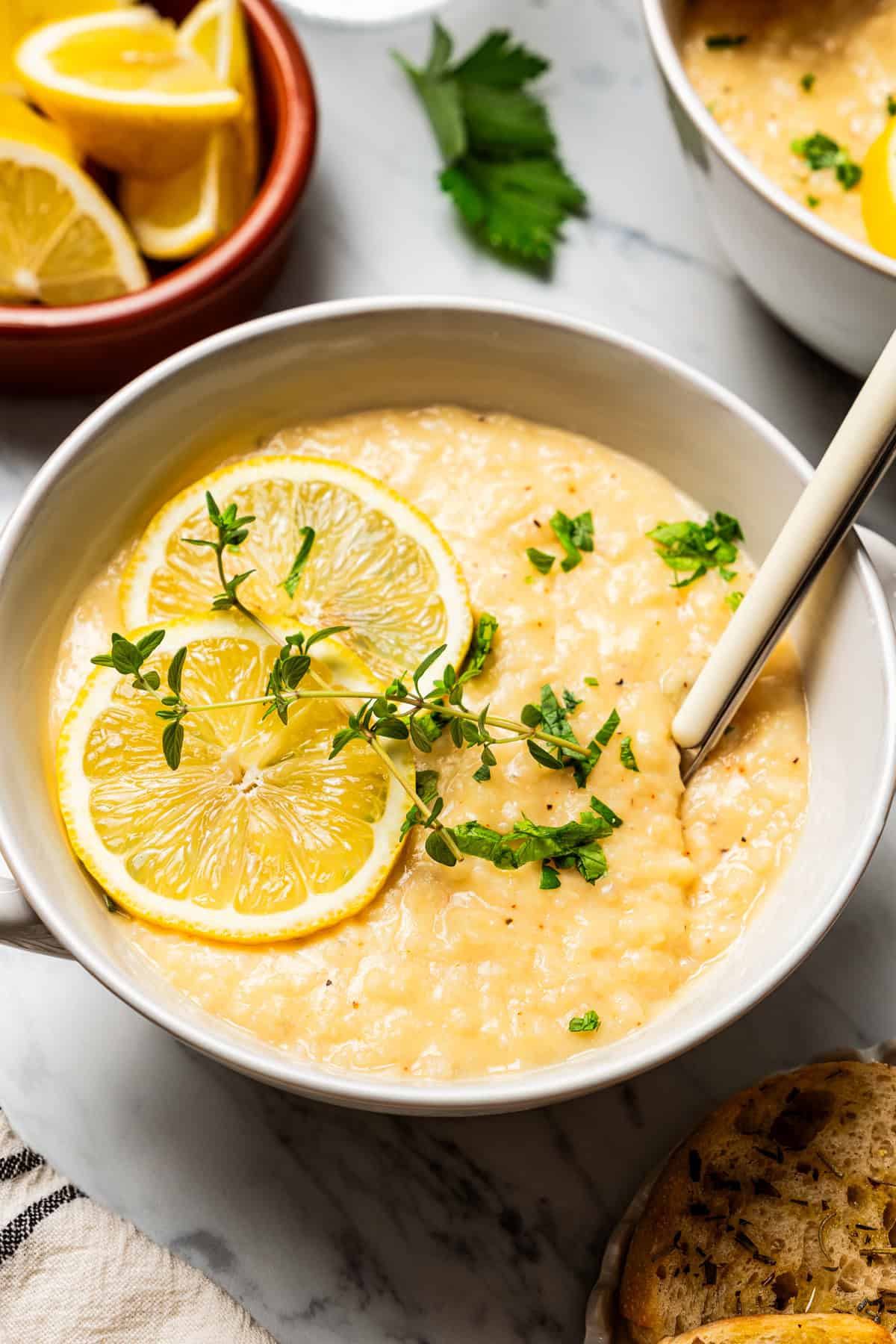 Lemon Rice Soup in a bowl with a garnish of lemon slices and green herbs.