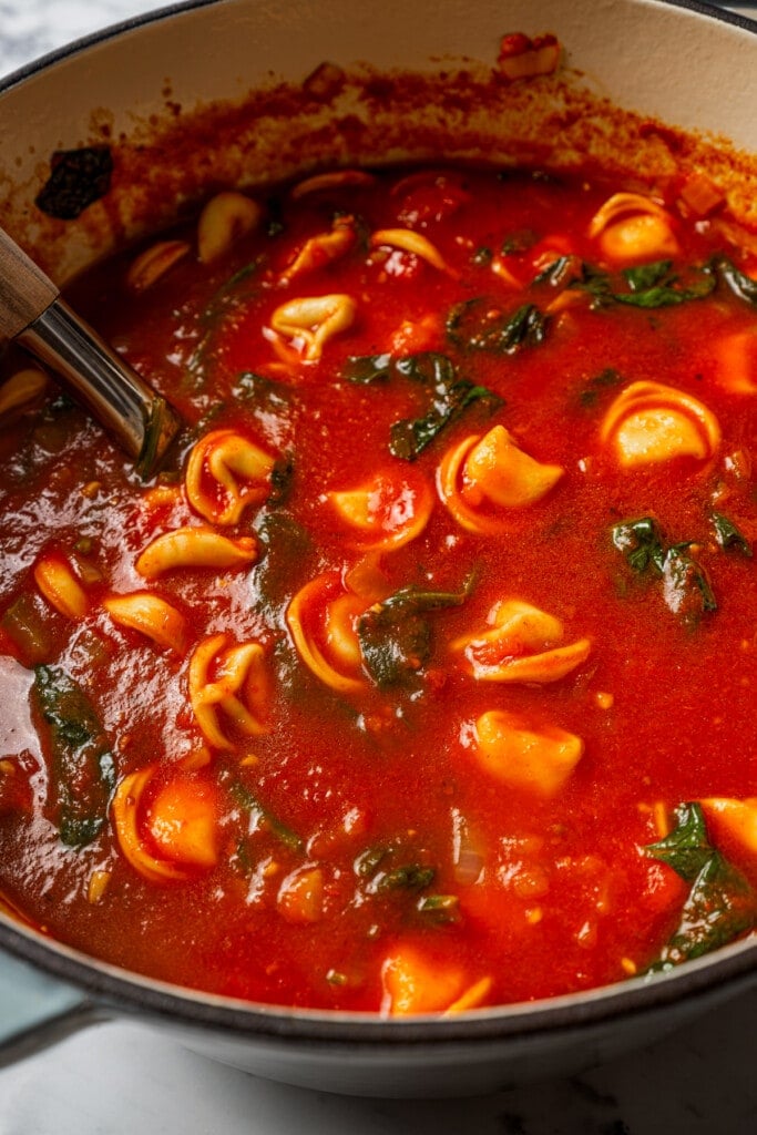 Up close image of Spinach Tortellini Tomato Soup cooking in a Dutch Oven.