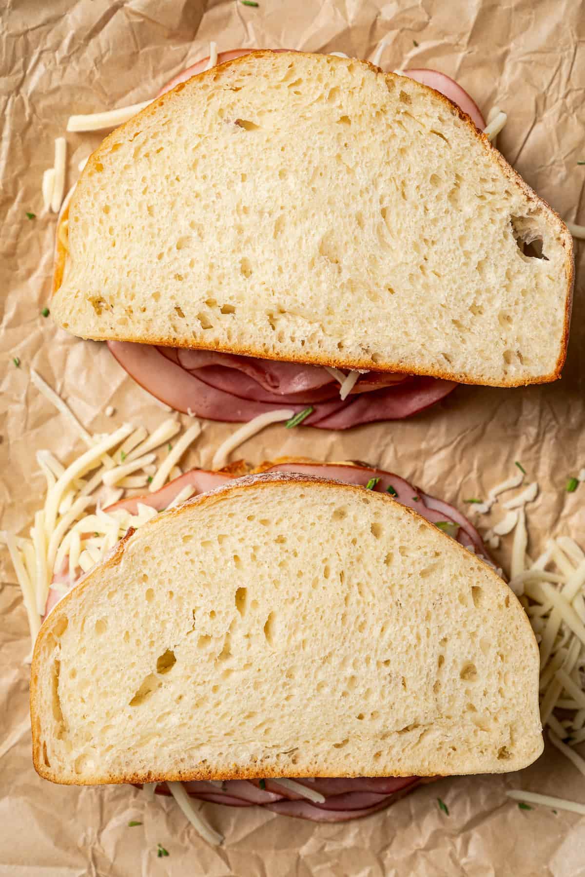 Overhead view of two assembled apple grilled cheese sandwiches on a piece of parchment paper.