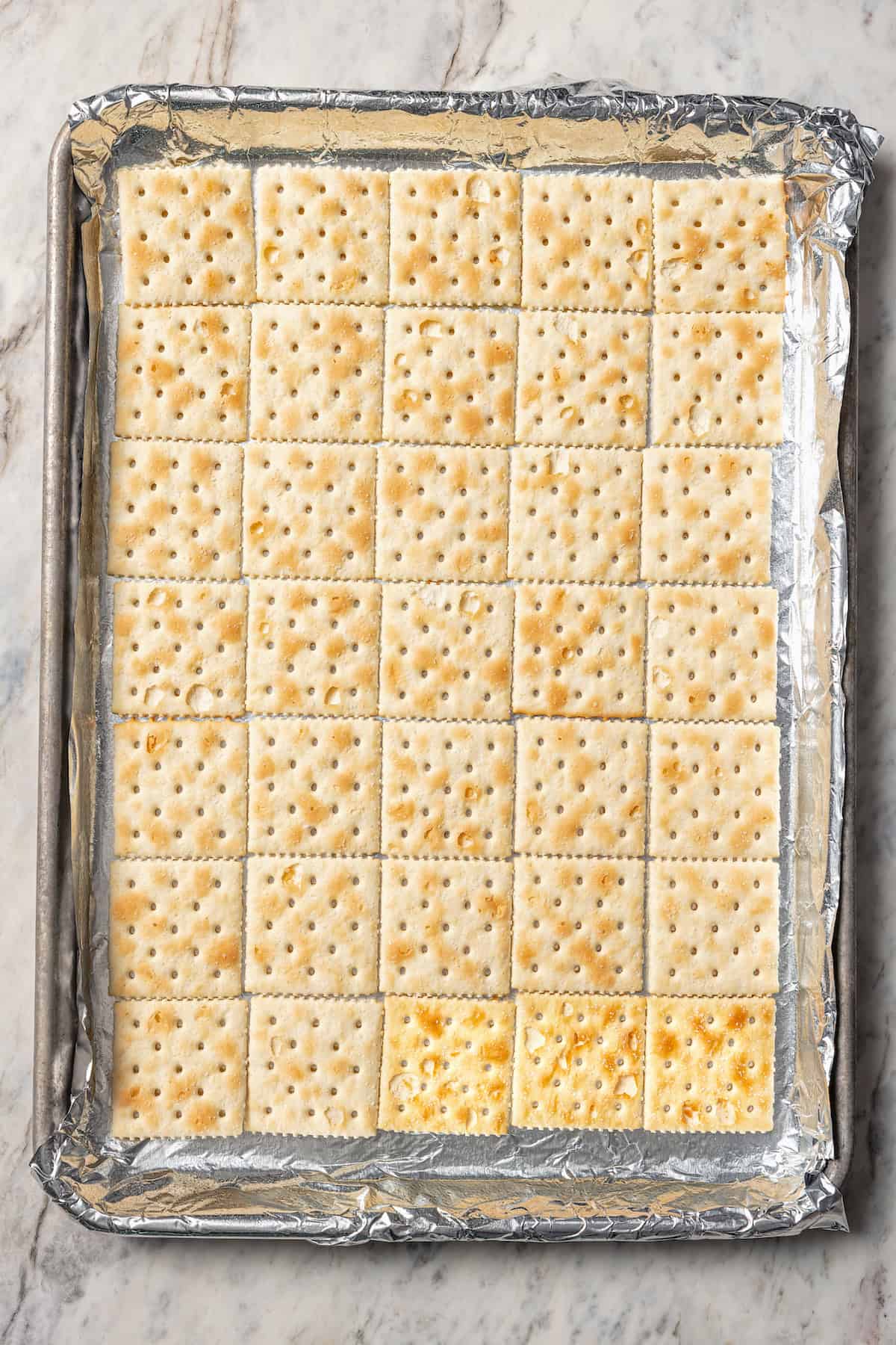 Saltine crackers arranged in a foil-lined sheet pan.