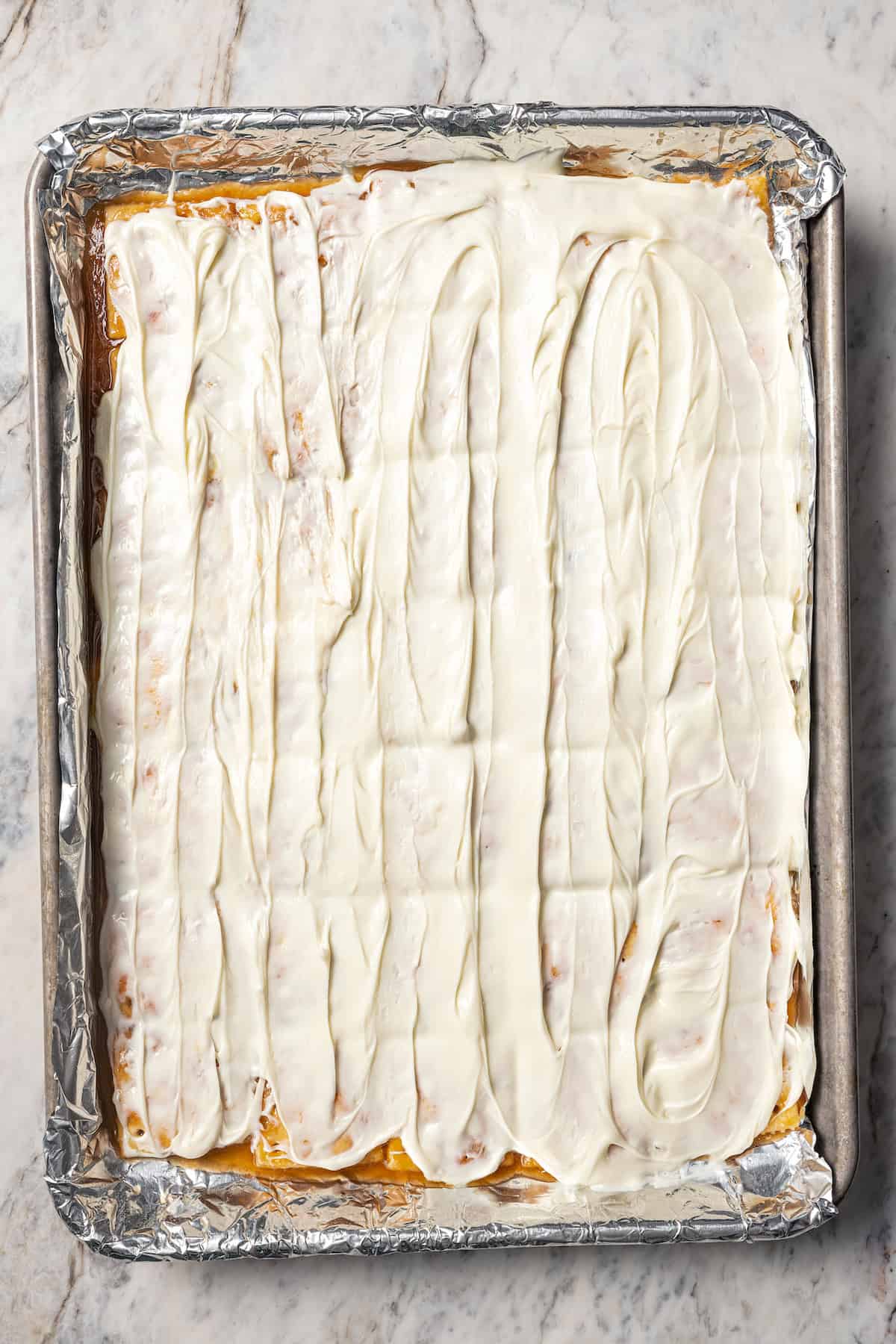 Overhead view of saltine crackers topped with a layer of white chocolate on a baking sheet.