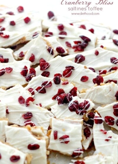 A close up of pieces of Saltine Toffee topped with white chocolate and cranberries