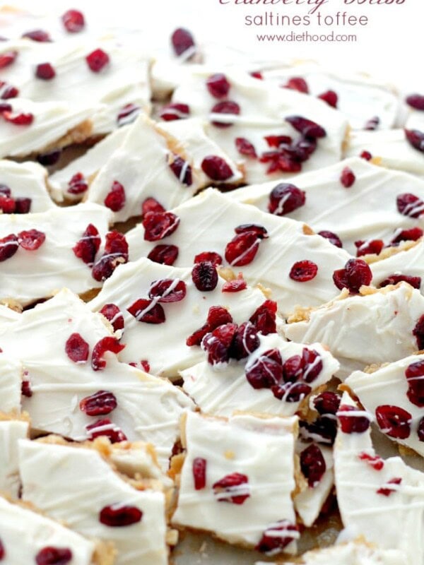 A close up of pieces of Saltine Toffee topped with white chocolate and cranberries