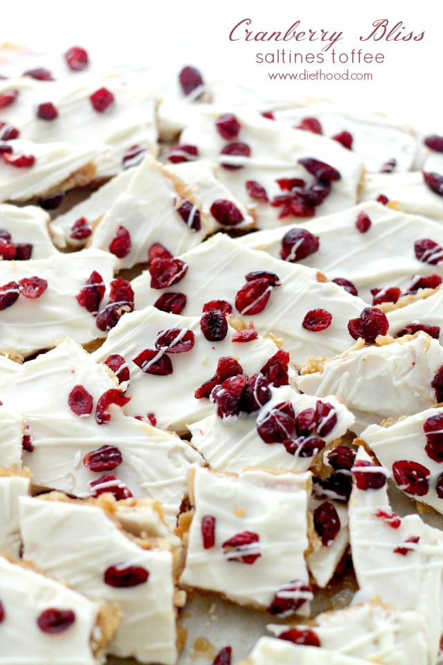 A close up of pieces of Saltine Toffee topped with white chocolate and cranberries
