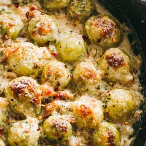 Cheesy Brussels Sprouts with Bacon title card featuring a close up of roasted Brussels sprouts covered in cheese sauce.