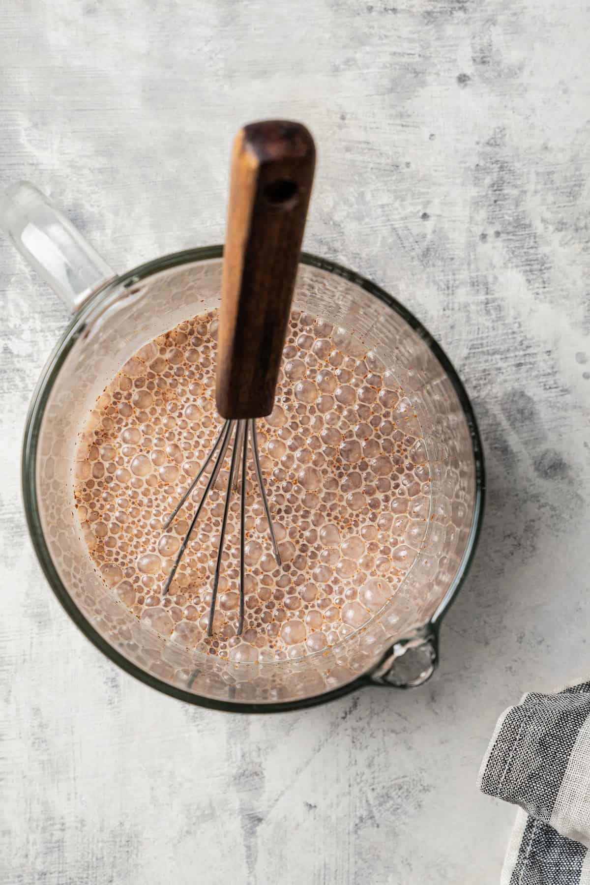 Eggnog mixture whisked together in a glass bowl.