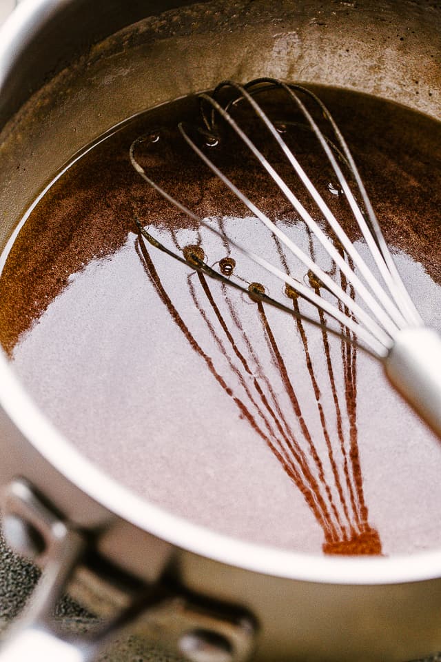 A whisk resting in a saucepan of honey mustard glaze.