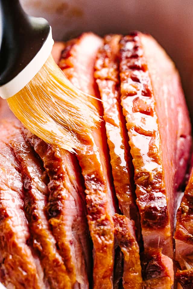 Ham slices being brushed with honey glaze.