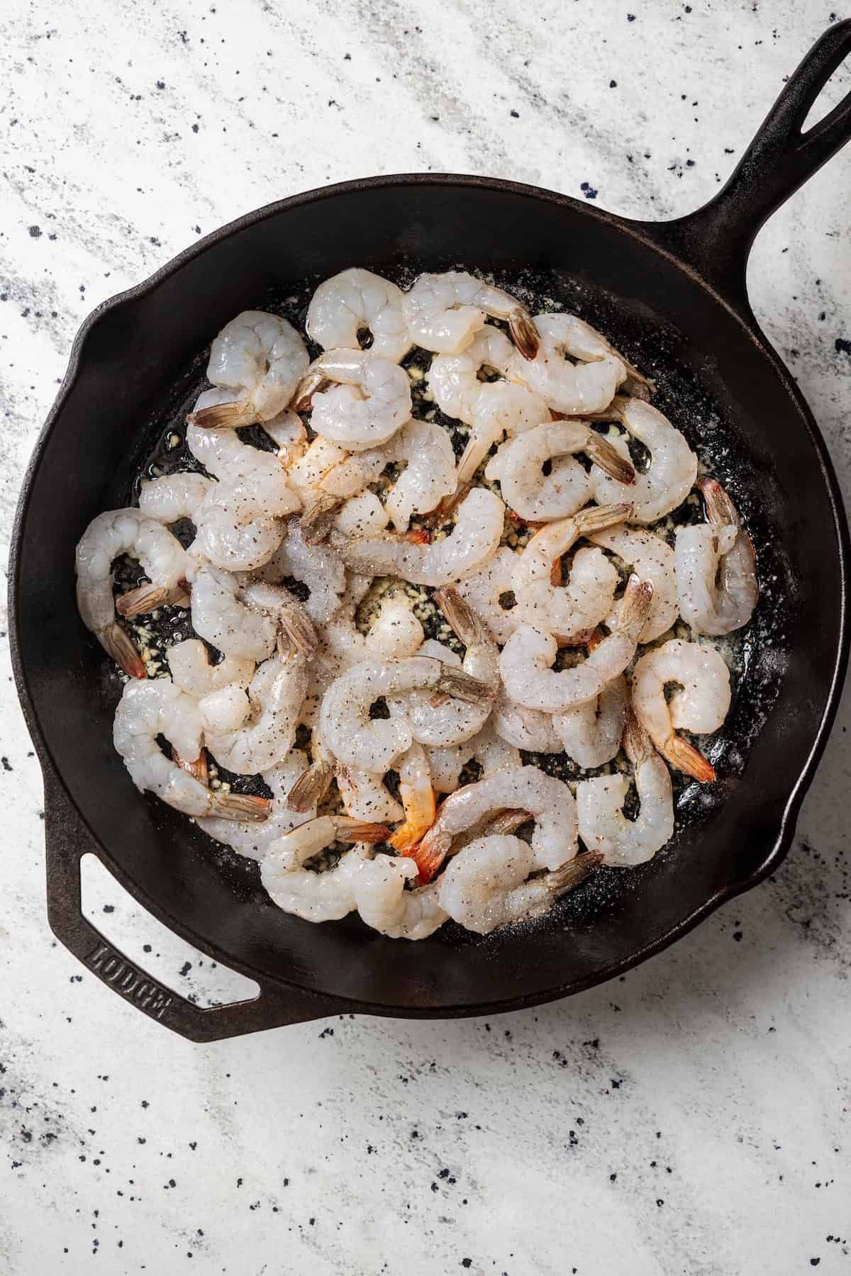 Raw shrimp added to a skillet.