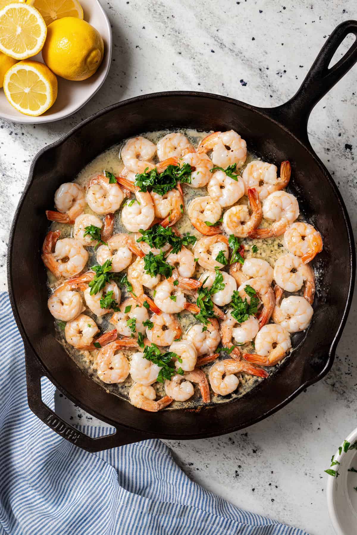 Parsley added to lemon garlic shrimp in a skillet.