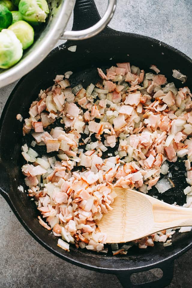 Diced bacon is cooked in a cast iron skillet.