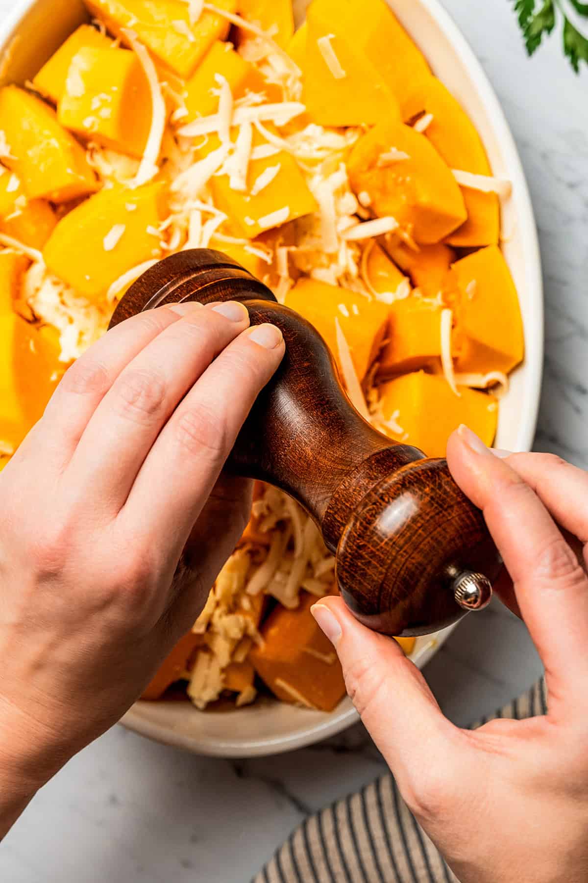 Adding cracked pepper to diced butternut squash.