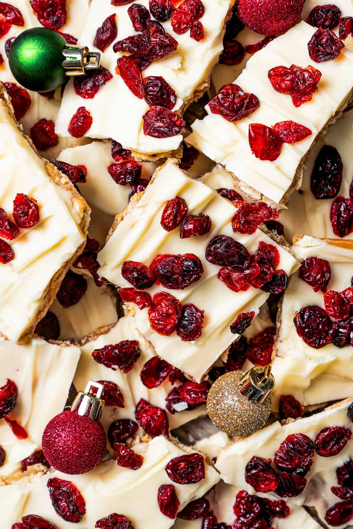 Overhead view of Christmas crack scattered on a sheet pan with small red and green Christmas ball ornaments.