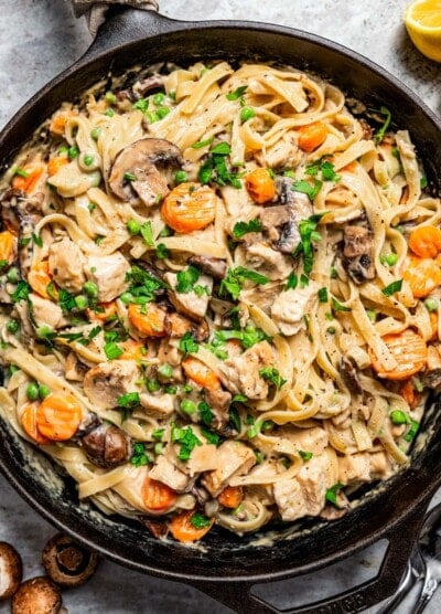 Overhead image of a cast iron skillet filled with pasta and turkey chunks in a creamy sauce to make turkey tetrazzini.
