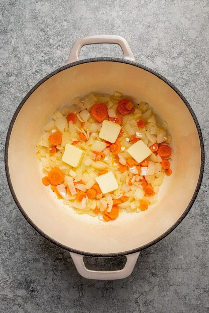 Sauteed carrots and onions in a large pot with butter.