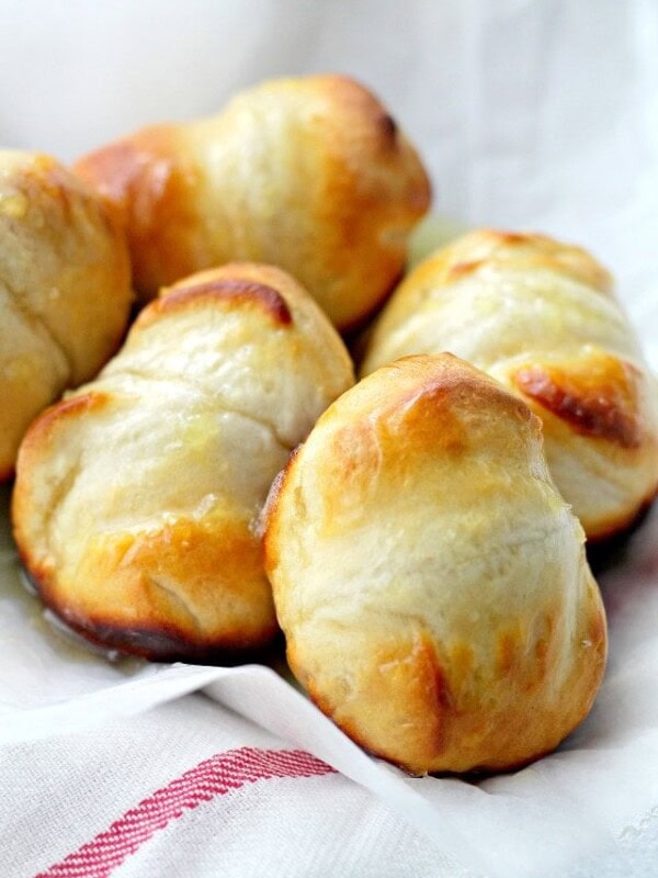 Orange dinner rolls arranged on a kitchen towel.