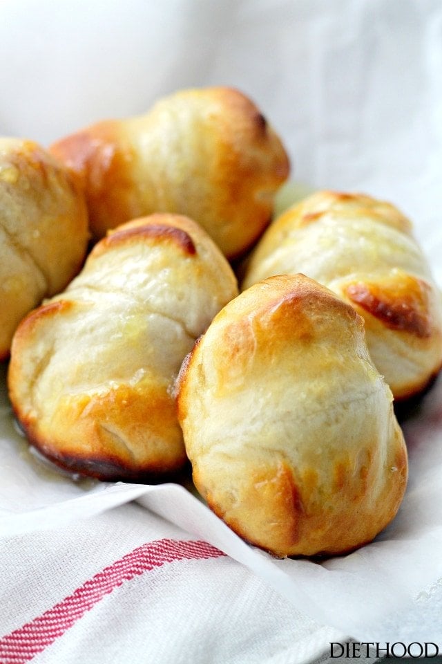 Orange dinner rolls arranged on a kitchen towel.