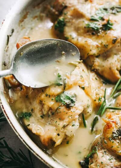 spooning garlic sauce over pan seared chicken thighs.